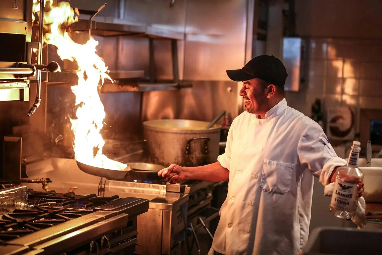 Chef finishing a dish over open flame